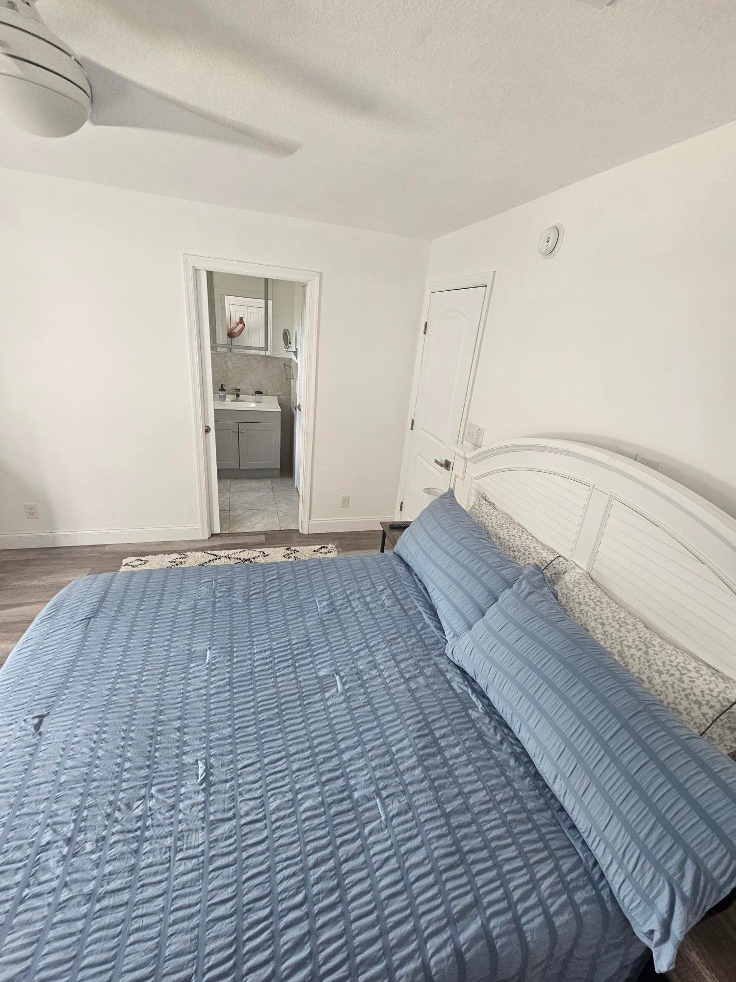 A bedroom with blue linen and an en suite door