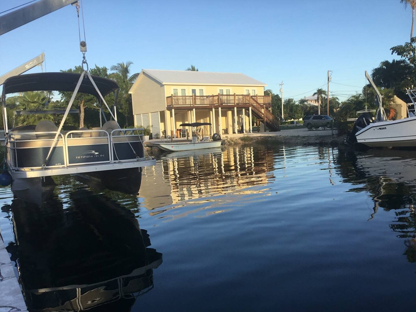 The canal behind the house, with a boat on the lift and the butter-yellow house on its stilts