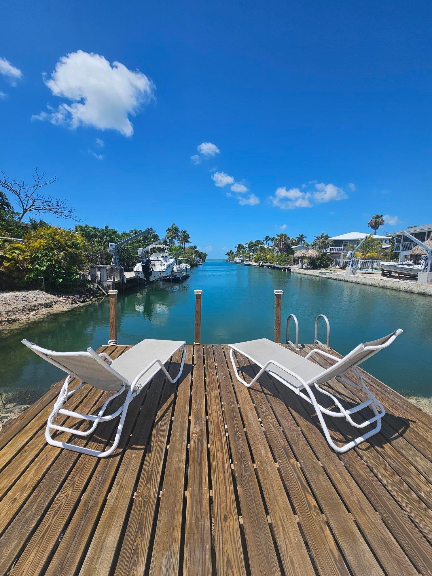 Two sun loungers on the dock, with the swim ladder into the canal